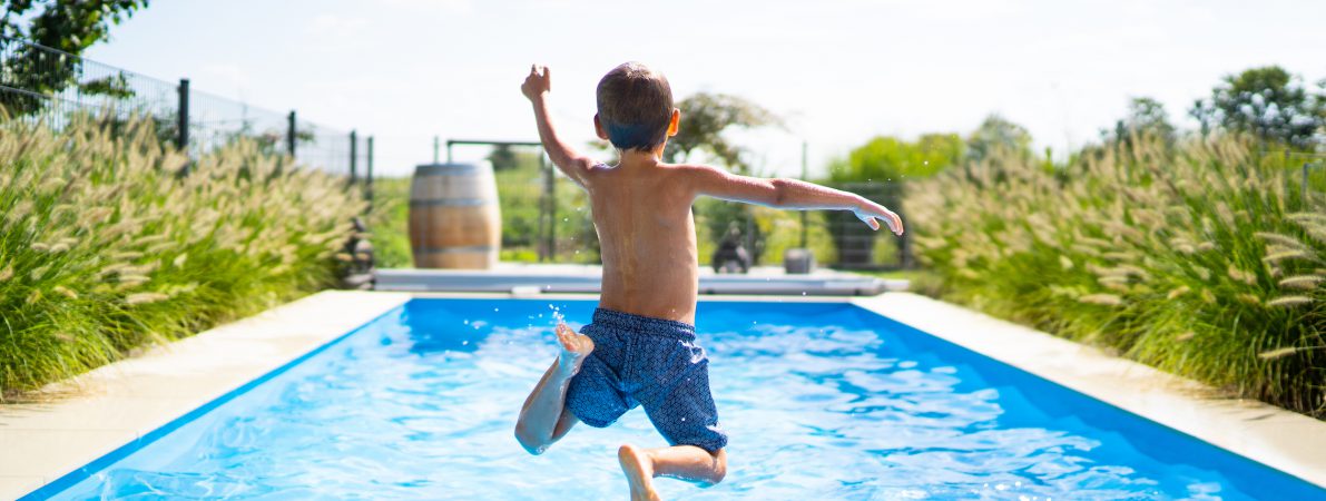 back view of 4 year old boy jumping into private pool - boy is unrecognizable so can be used anonymous summer fun series
