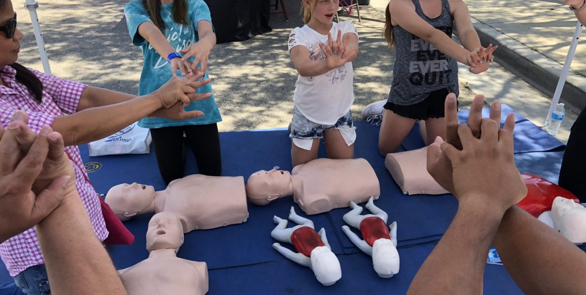 Three young girls demonstrating the correct hand technique for hands only CPR